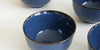 Close up of a dark blue ceramic cup with a black rim.
