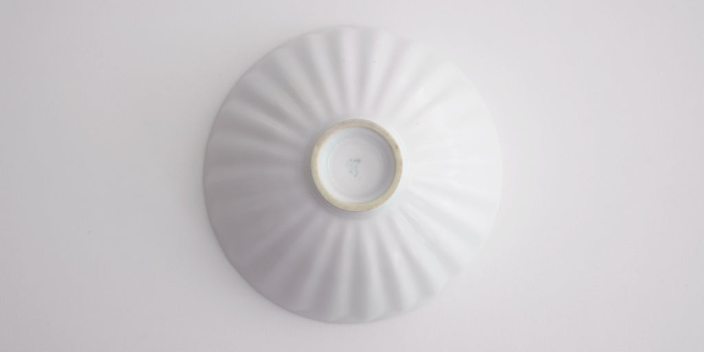 The bottom of a white tea bowl with subtle ridges radiating out from the center. Xu De Jia's Maker's mark is painting in light blue in the base.