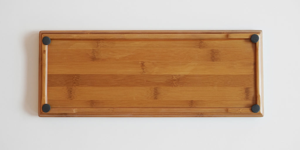 Underside of a bamboo tray, with rubber feet at each corner. The base is made up of multiple strips of bamboo side by side.