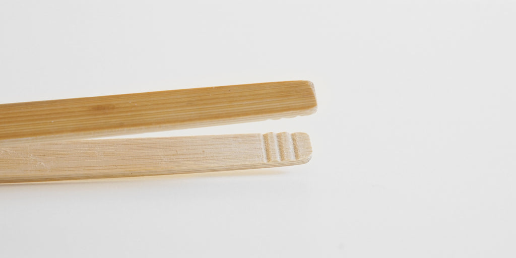 Close up of the tips of a pair of bamboo tongs. The inside is textured to improve grip.