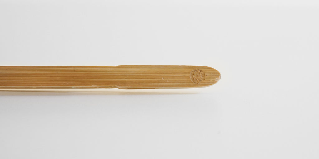 Close up of the join of a pair of bamboo tea tongs. A small maker's mark is carved into the top.