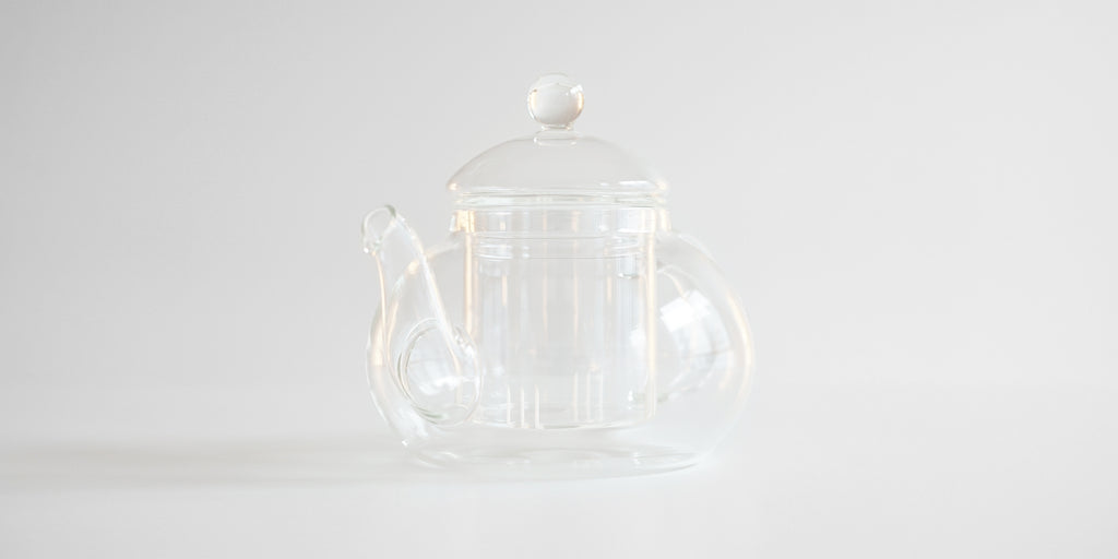 Front view of a glass teapot showcasing the spout, with a dip shaped into the bottom to prevent dribbling.