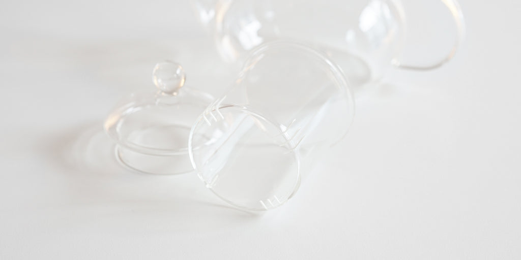 Close up of the infuser for a glass teapot. It has 12 slits cut into the bottom to allow water to pass through.