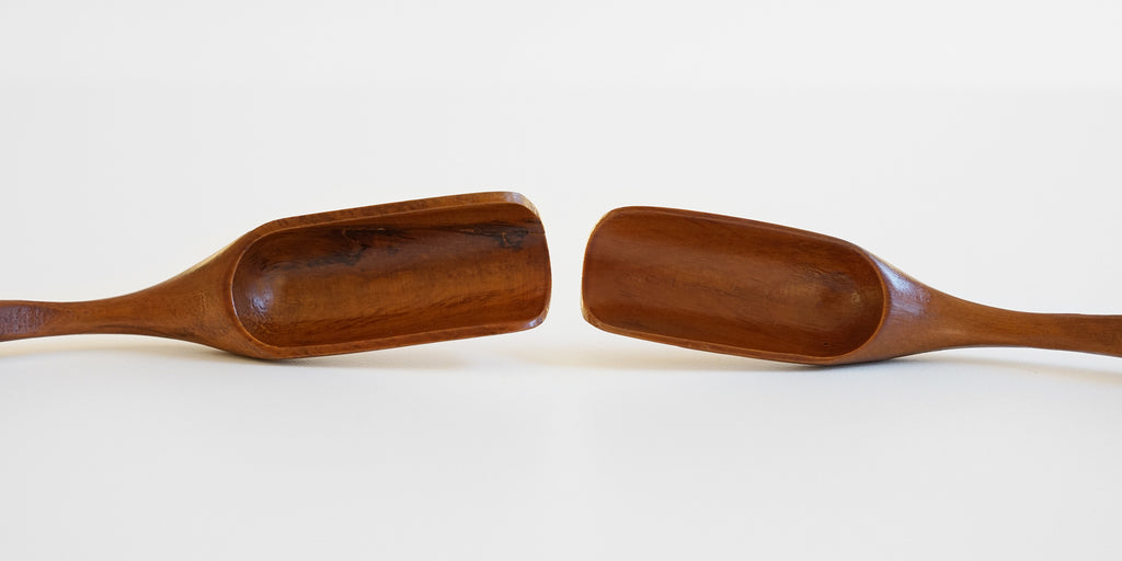 Two cherrywood scoops with darker brown grain patterning. The scoops face each other in the middle, and the handles extend off frame.