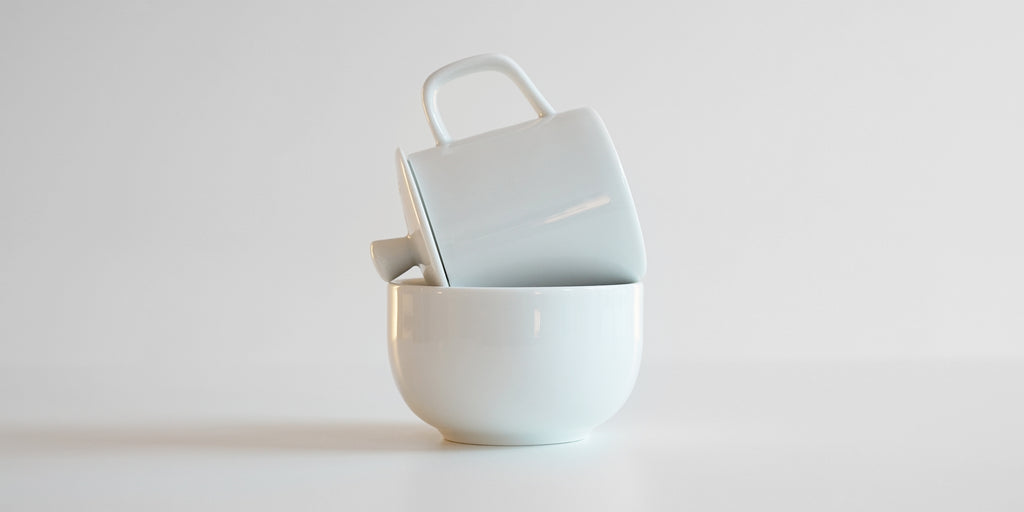 Side view of the Competition set in use. The base of the cup and the handle of the lid rest on either edge of the bowl, allowing the tea inside to be decanted hands-free.