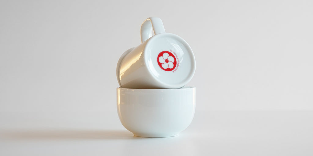 Rear view of the competition set in use. The brewing vessel rests on top of the bowl to decant, showing the printed logo on its base.
