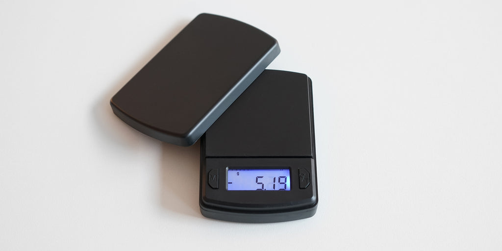 A matte black scale with a lid placed off-kilter resting on the scale.