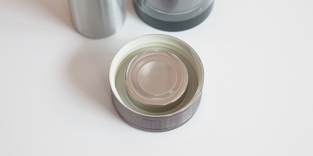 Top down view of the inside of the lid. It has threading set into it, a silicone gasket, and a reflective silver finish where it is exposed to tea.