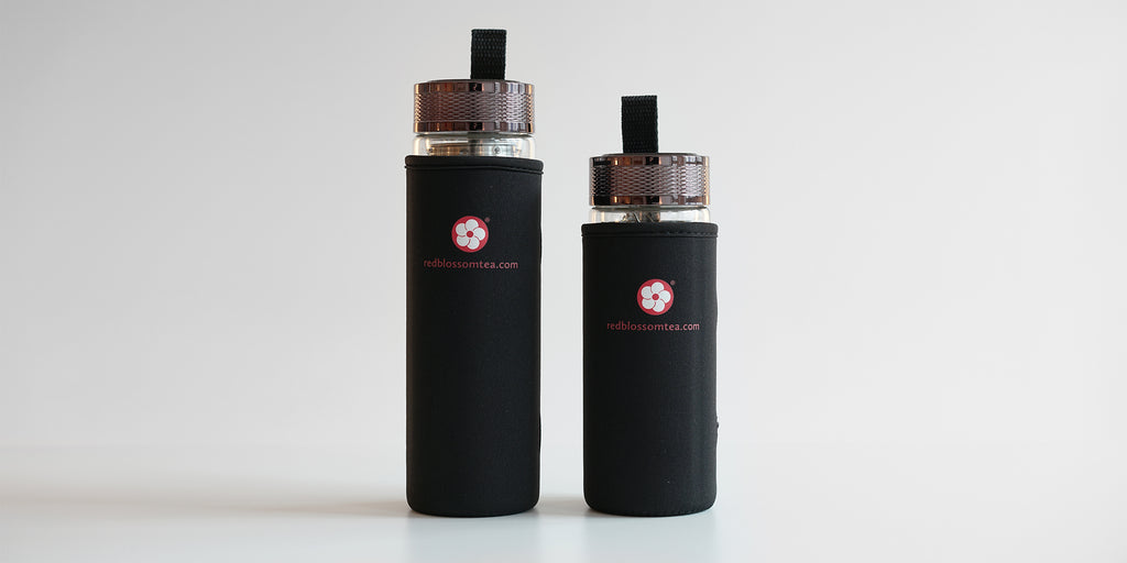 Two fully assembled thermoses, showing the Red Blossom Tea Company logo in red on the black cozys. The one on the left is large, and the one on the right is slightly shorter.