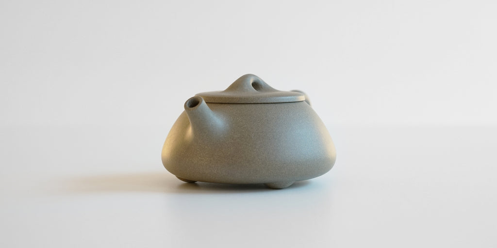 Front view of a gray duanni yixing teapot, showing its short spout.