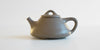 Side view of a gray duanni yixing teapot, showing its triangular shape.