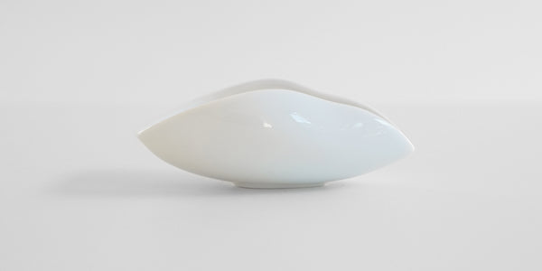 Side view of a white ceramic tea dish.
