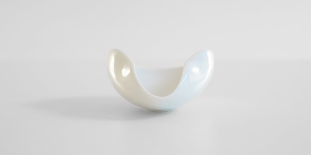 Front view of the pouring spout of a white ceramic tea dish.