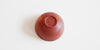 The bottom of a terracotta-colored teacup, with a maker's mark stamped into the foot.
