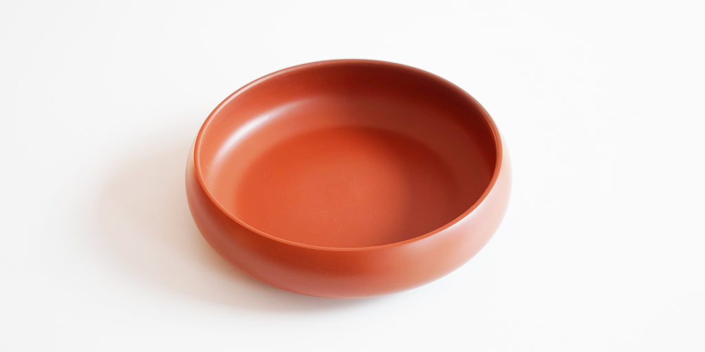 A round terracotta-colored tea tray on a blank background.