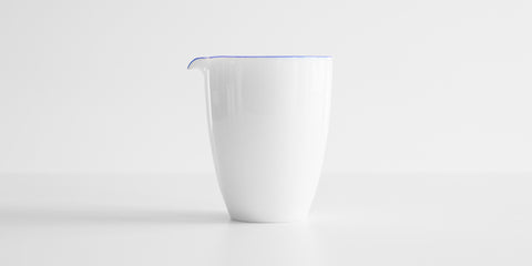 Side view of a white porcelain server with a blue ring around the top edge.