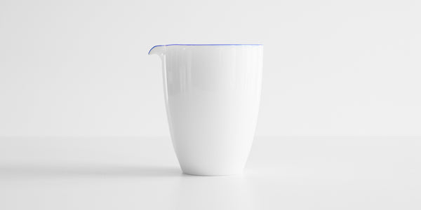 Side view of a white porcelain server with a blue ring around the top edge.
