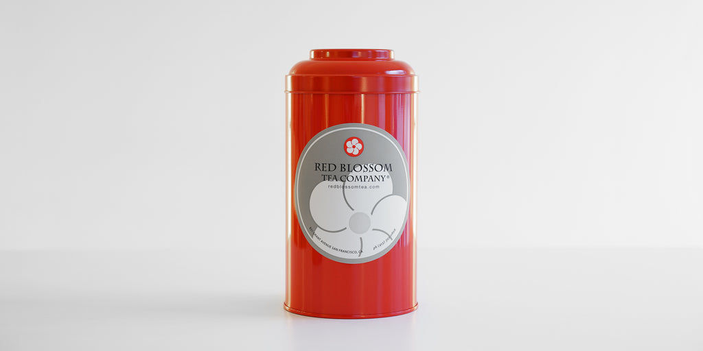 A red canister with a Red Blossom Tea Company label in the middle.