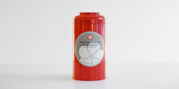 A red canister with a Red Blossom Tea Company label in the middle.