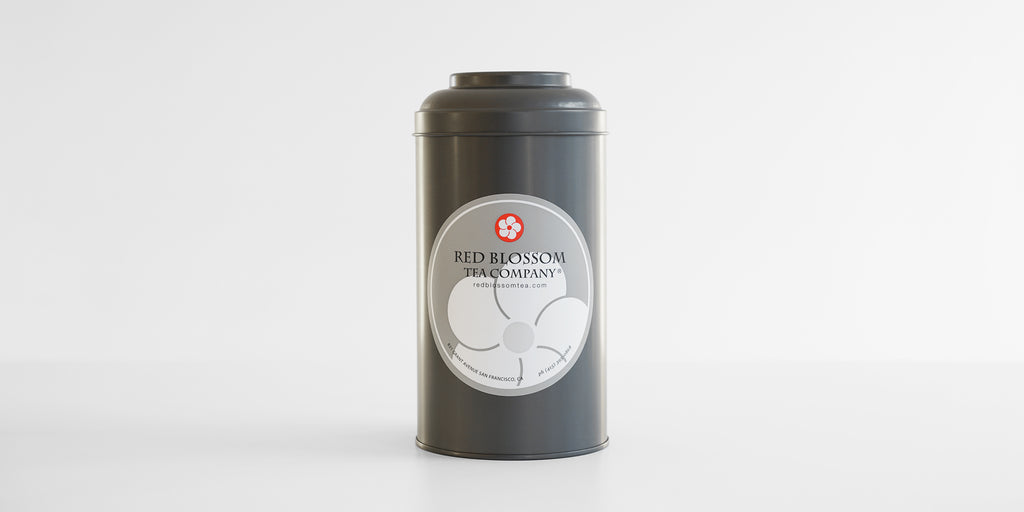 Front view of a gray metal canister, with a Red Blossom Tea Company logo in the middle.