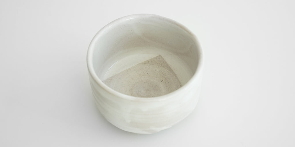 View of the inside of a straight-sided white bowl. The bottom has a light gray geometric pattern.