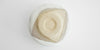 The bottom of a white bowl. The foot is a beige color, and unglazed.