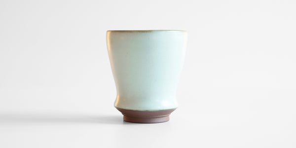 Side view of a small blue-green celadon drinking cup in a shape similar to a tulip glass.