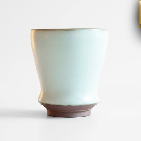 Side view of a small blue-green celadon drinking cup in a shape similar to a tulip glass. A gold ribbon in the top right corner reads "New Arrival"