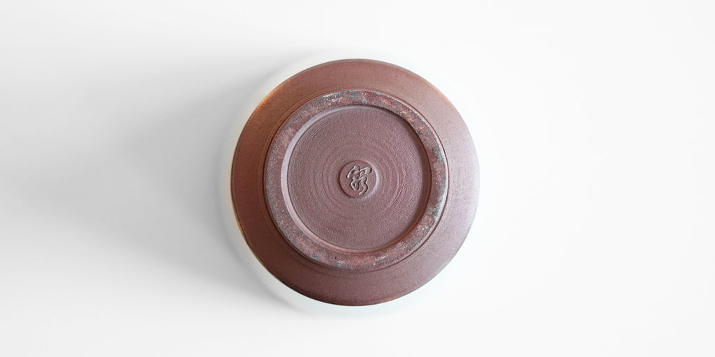 The bottom of a celadon drinking cup, with Xu De Jia's maker's mark stamped into the unglazed foot.