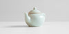 A front-view of a celadon teapot showing the spout.