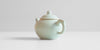 A back view of a celadon teapot showing the handle.