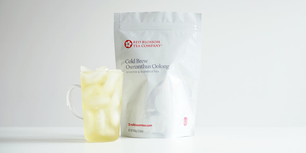 A glass cup filled with ice and osmanthus oolong tea next to a package of Cold Brew Osmanthus Oolong.