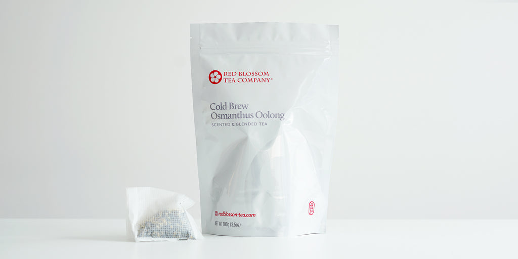 A large teabag filled with osmanthus oolonf tea next to a package of Cold Brew Osmanthus Oolong.