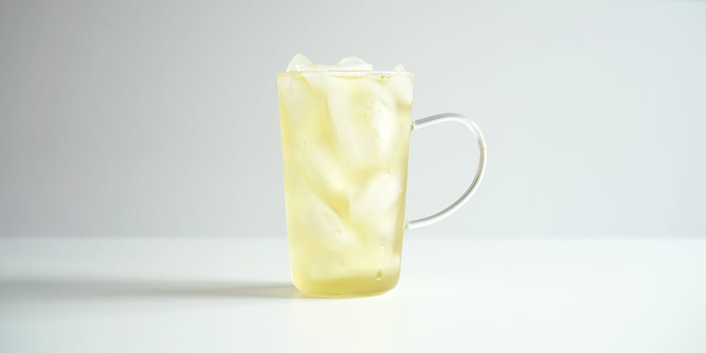A glass cup filled with ice and osmanthus oolong tea on a white background.