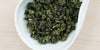 A white dish containing dry Formosa oolong tea leaves.