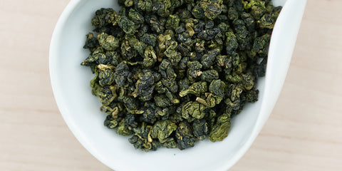 A white dish containing dry Formosa oolong tea leaves.