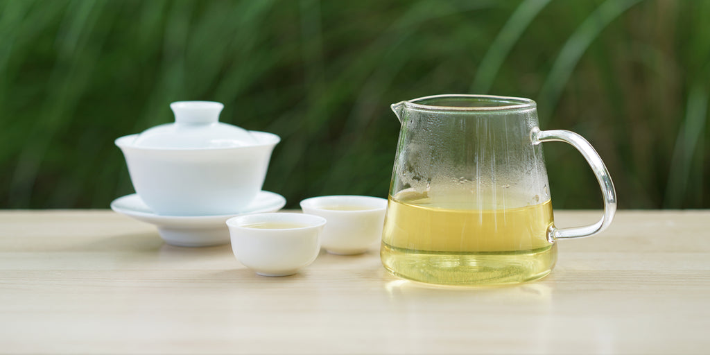 From left to right, a gaiwan, two teacups, and a glass server. The teacups and server have Formosa oolong tea in them.