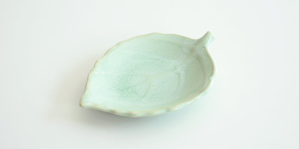 Front view of a light green trivet in the shape of a leaf, with raised veins.