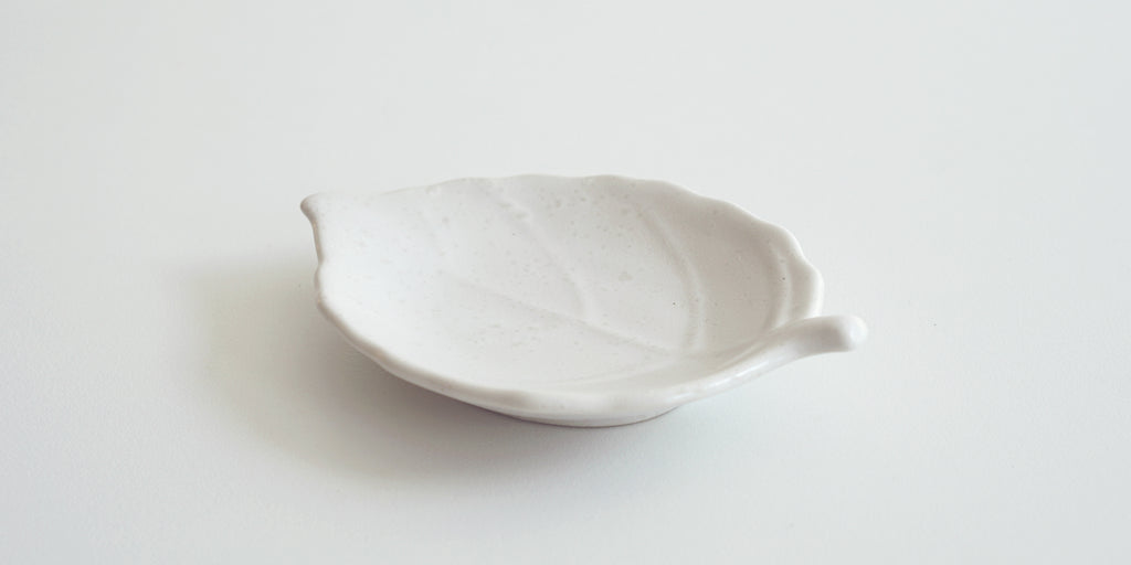 Rear view of a white trivet in the shape of a leaf, with raised veins.
