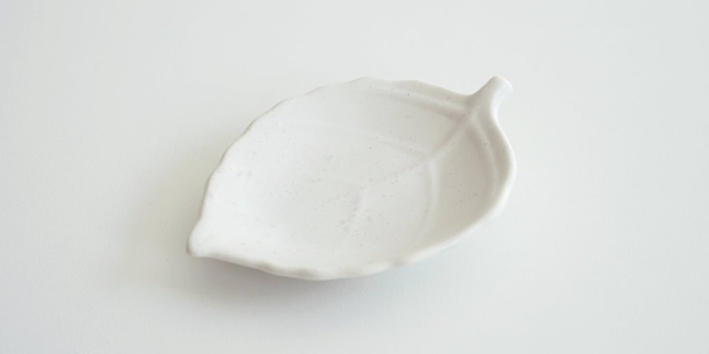 Front view of a white trivet in the shape of a leaf, with raised veins.