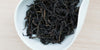 A white dish containing dry Phoenix oolong tea leaves.