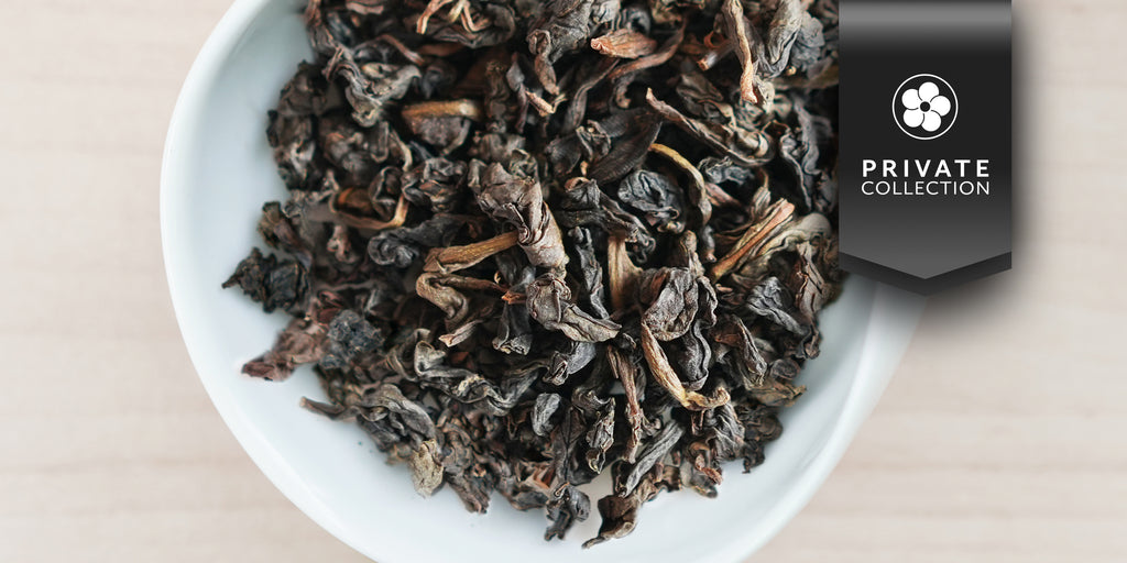 A white dish containing dry aged Tieguanyin tea leaves. A black ribbon in the top right corner reads “Private Collection”