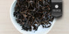 A white dish containing dry aged Formosa oolong tea leaves. A black ribbon in the top right corner reads “Private Collection".