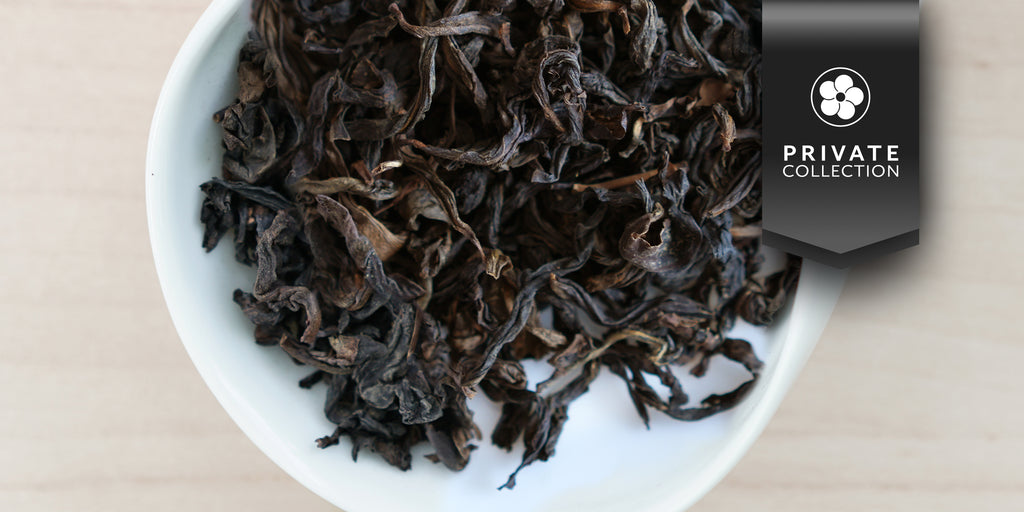 A white dish containing dry aged Formosa oolong tea leaves. A black ribbon in the top right corner reads “Private Collection