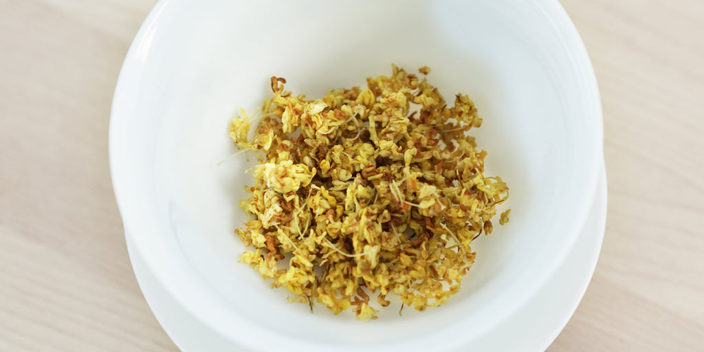 A top-down photo of brewed osmanthus flowers in a gaiwan.