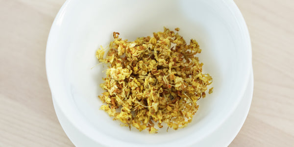 A top-down photo of brewed osmanthus flowers in a gaiwan.