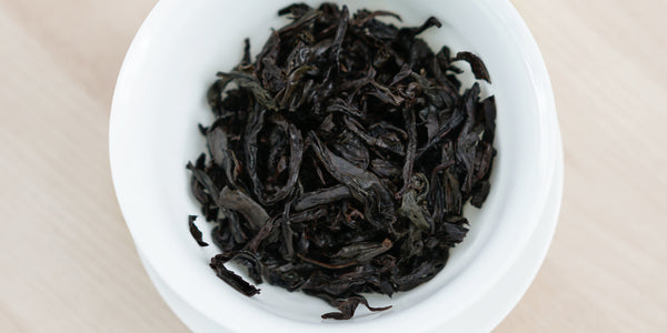 A top-down photo of brewed Wuyi oolong tea leaves in a gaiwan.