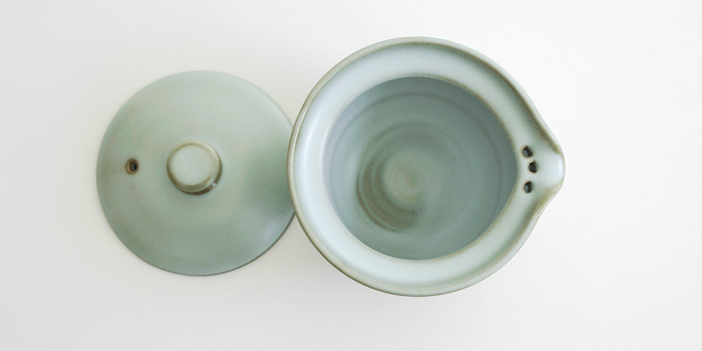 Top down view of the shiboridashi with the lid off to the side, showing the brown lip and the iron spot patterns inside.