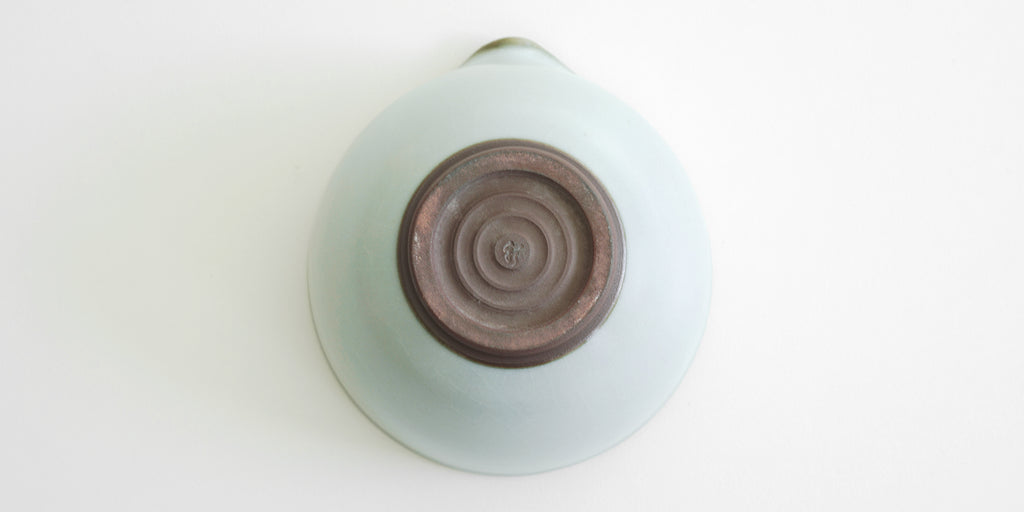 The bottom of a blue-green celadon shiboridashi, with Xu De Jia's maker's mark stamped into the unglazed base.