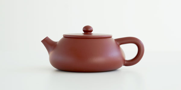 Side view of a terracotta-colored yixing pot, highlighting the flat shape.